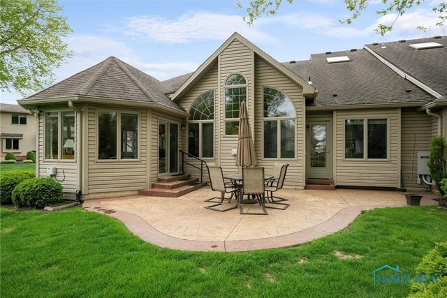 back of property with a yard, entry steps, a shingled roof, and a patio area