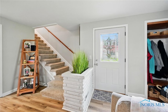 foyer featuring baseboards, stairs, and wood finished floors