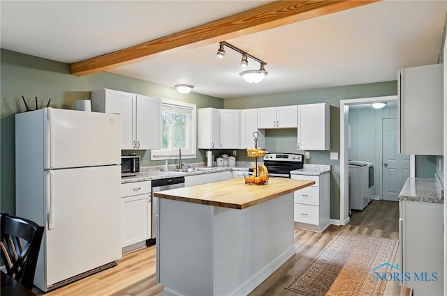 kitchen with wood counters, washer and clothes dryer, stainless steel appliances, and white cabinets