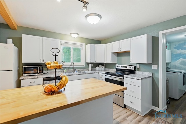 kitchen with light wood finished floors, a sink, wood counters, white cabinetry, and appliances with stainless steel finishes