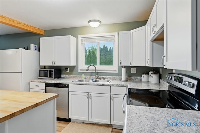 kitchen featuring a sink, stainless steel appliances, white cabinetry, and butcher block countertops