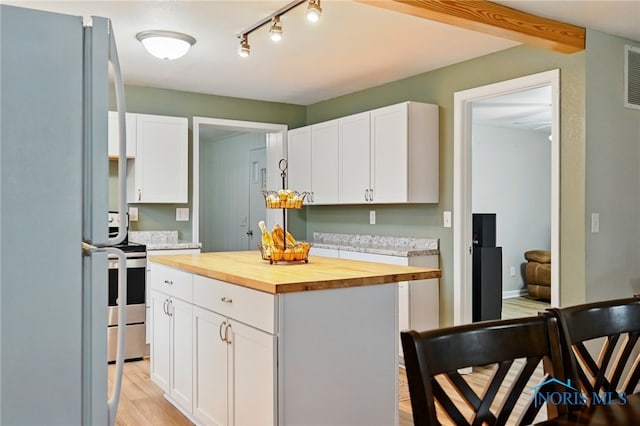 kitchen with wood counters, stainless steel electric range oven, freestanding refrigerator, and white cabinets