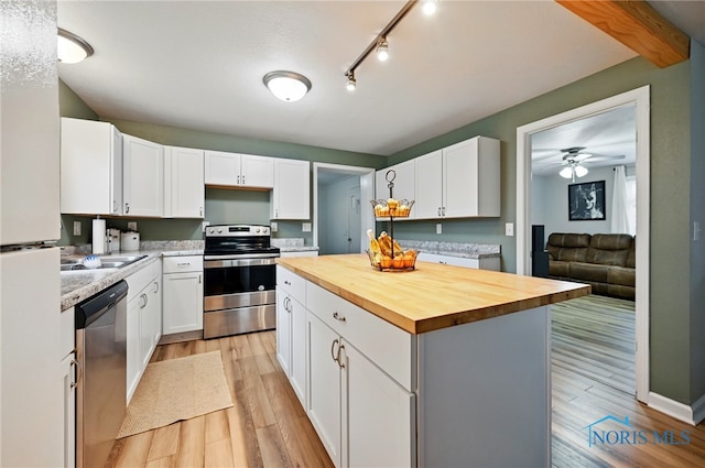 kitchen with light wood-style floors, butcher block counters, white cabinetry, and appliances with stainless steel finishes