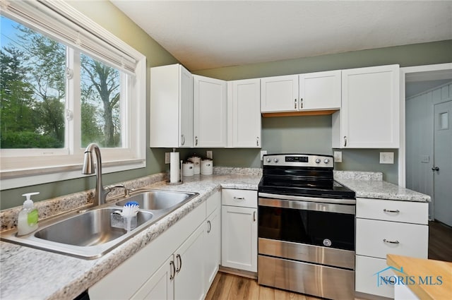 kitchen featuring a sink, white cabinetry, light countertops, and electric stove