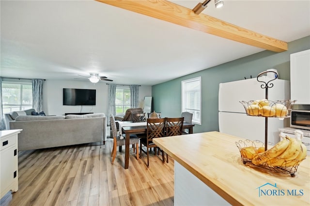 kitchen with freestanding refrigerator, beamed ceiling, white cabinets, wooden counters, and light wood-style floors