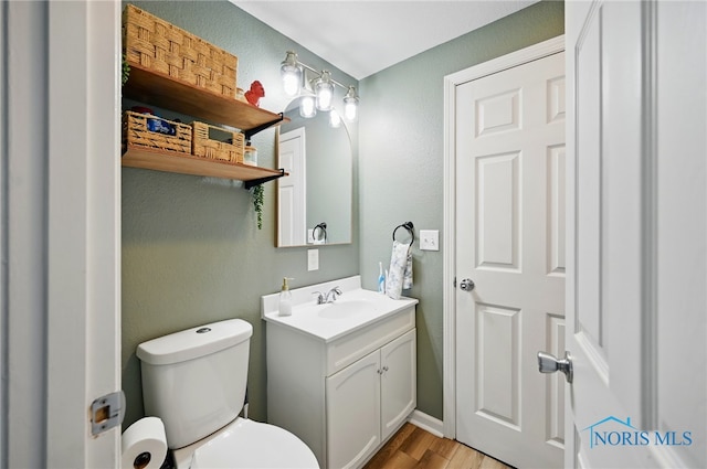 bathroom with toilet, vanity, and wood finished floors