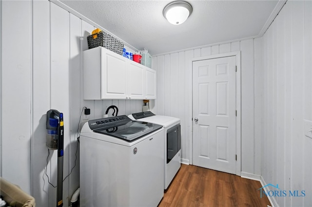 washroom featuring washing machine and clothes dryer, a textured ceiling, dark wood finished floors, and cabinet space