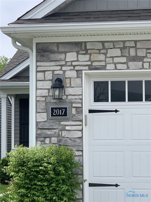 entrance to property with stone siding and a shingled roof