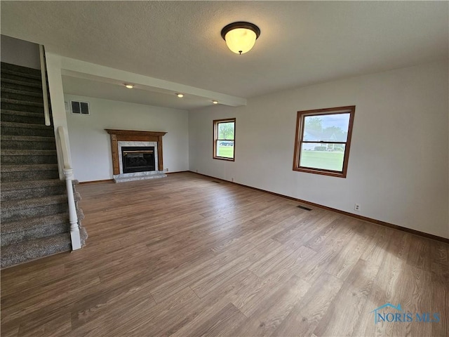 23675 W State Route 51, Genoa, OH 43430 - unfurnished living room with wood finished floors, a glass covered fireplace, stairway, baseboards, and recessed lighting