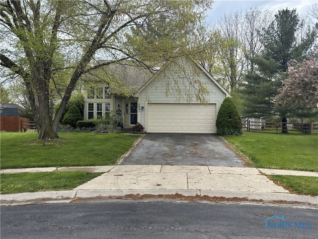 view of front of home with a garage, driveway, fence, and a front yard