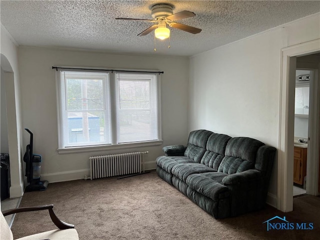 living area featuring a textured ceiling, ceiling fan, and radiator heating unit