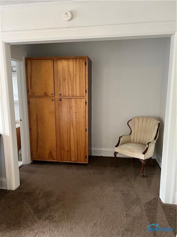 living area featuring dark colored carpet and baseboards