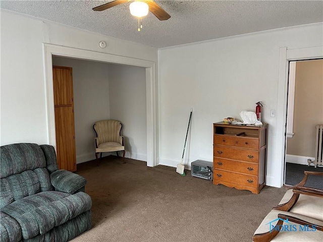 sitting room with a textured ceiling, radiator heating unit, ceiling fan, and carpet floors