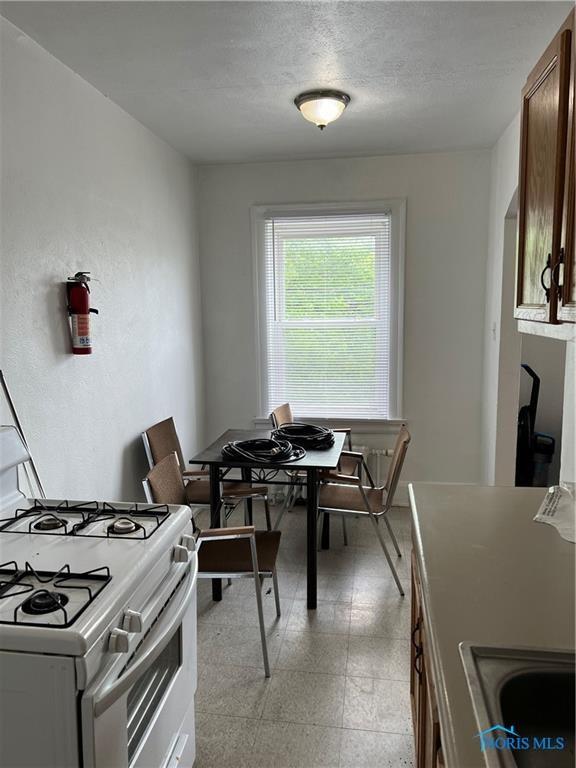 2289 Upton Ave, Toledo, OH 43606 - kitchen featuring white range with gas cooktop, light floors, and a textured ceiling