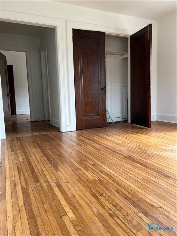unfurnished bedroom with light wood finished floors, a closet, and baseboards