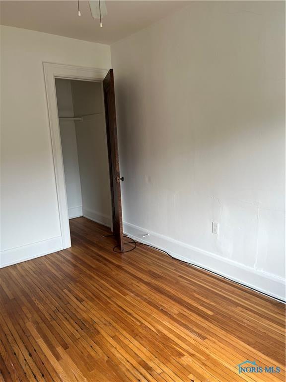 unfurnished bedroom featuring baseboards, a closet, and hardwood / wood-style flooring