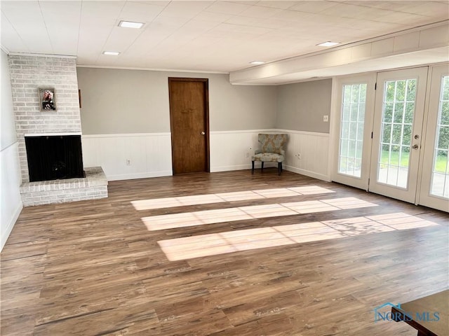 12982 State Route 34, Bryan, OH 43506 - unfurnished living room with wood finished floors, wainscoting, a brick fireplace, and crown molding