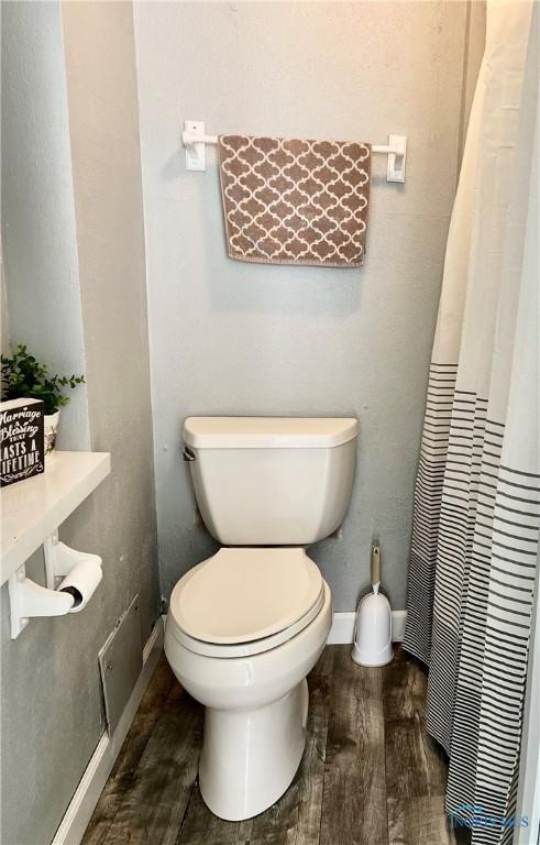 12982 State Route 34, Bryan, OH 43506 - bathroom featuring wood finished floors, toilet, baseboards, and curtained shower