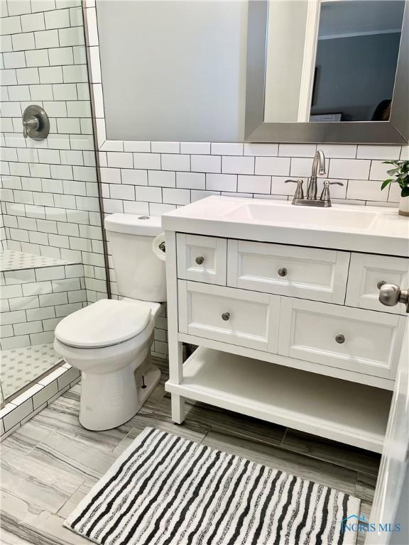 12982 State Route 34, Bryan, OH 43506 - full bath with a tile shower, vanity, tile walls, and toilet