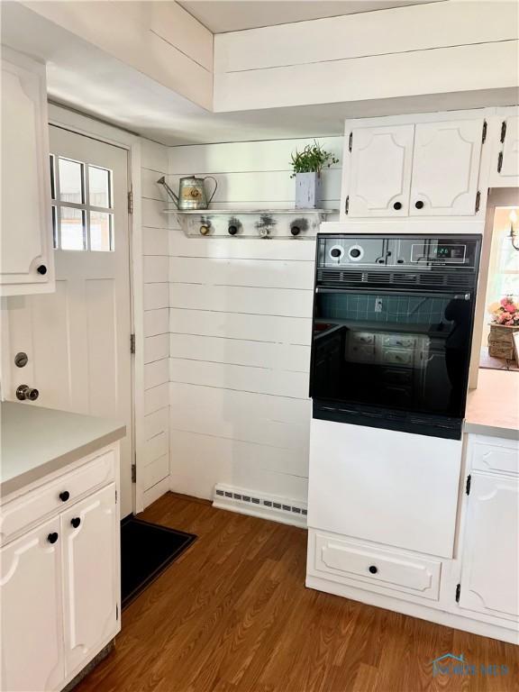 12982 State Route 34, Bryan, OH 43506 - kitchen with oven, white cabinets, light countertops, and dark wood-style floors