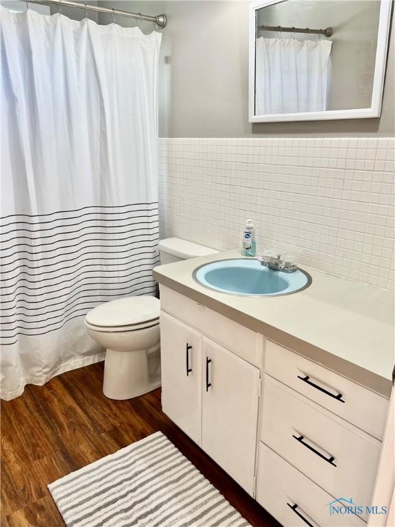 12982 State Route 34, Bryan, OH 43506 - bathroom with tile walls, toilet, vanity, wood finished floors, and a shower with curtain