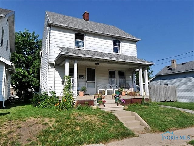 view of front of property featuring covered porch, fence, a chimney, and a front yard