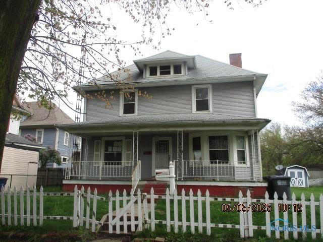 view of front facade featuring covered porch, a front yard, a chimney, and a fenced front yard