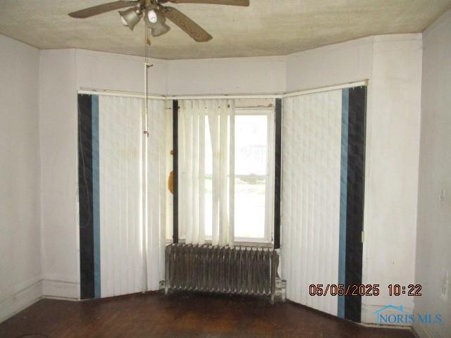 spare room with ceiling fan and radiator heating unit