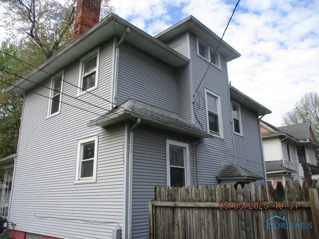 rear view of house featuring fence and a chimney