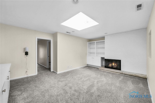 unfurnished living room with a skylight, visible vents, a fireplace, carpet flooring, and baseboards