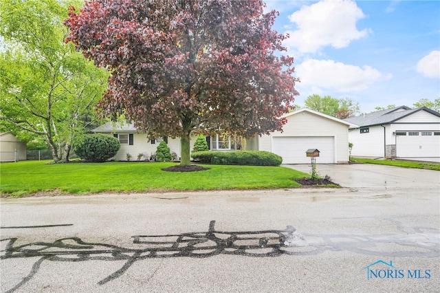 view of property hidden behind natural elements featuring driveway, an attached garage, and a front lawn