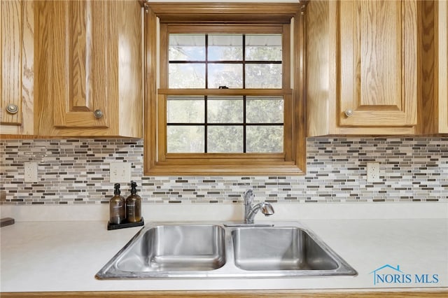 kitchen with light countertops, a sink, and backsplash