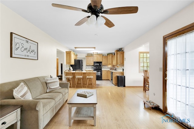 living area with ceiling fan and light wood finished floors