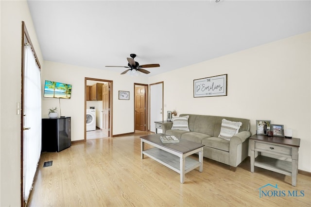 living area featuring washer / dryer, light wood-style floors, a ceiling fan, and baseboards