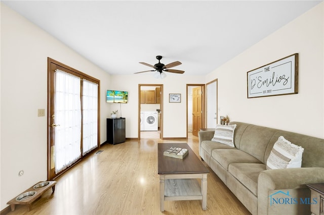 living area with washer / dryer, light wood-style flooring, ceiling fan, and baseboards