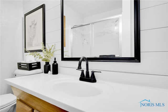 full bath with toilet, vanity, and a stall shower