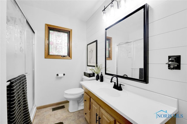 full bath featuring a shower stall, vanity, baseboards, and toilet