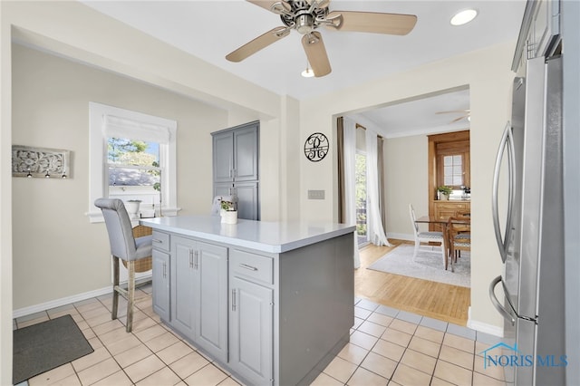 kitchen with freestanding refrigerator, a ceiling fan, light tile patterned floors, light countertops, and gray cabinets