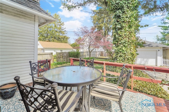 wooden terrace featuring outdoor dining area, fence, and an outbuilding