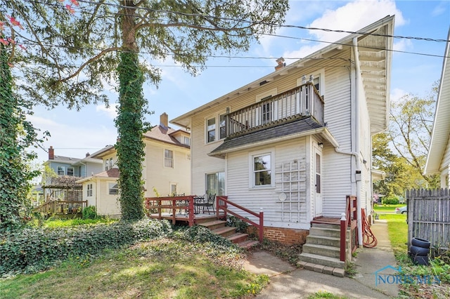 back of property featuring fence, a wooden deck, and a balcony