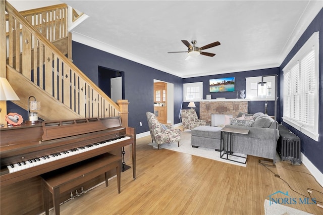 living room with stairs, wood finished floors, radiator, baseboards, and crown molding