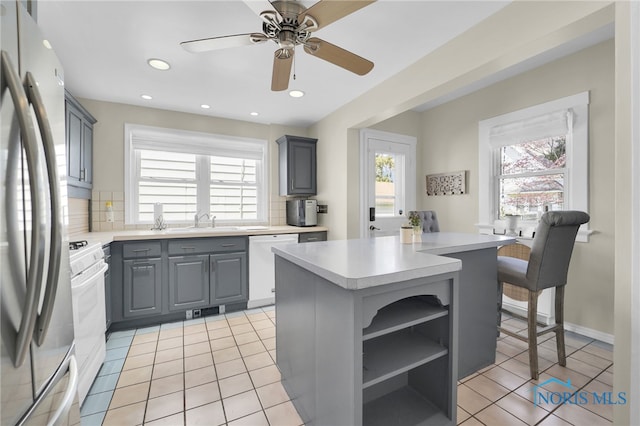 kitchen with gray cabinetry, light countertops, a wealth of natural light, and white appliances