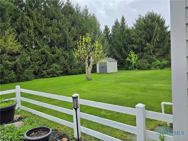 view of yard with fence private yard, a storage shed, and an outdoor structure