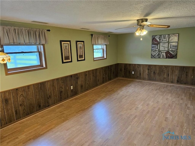 13941 Hannah Rd, Bowling Green, OH 43402 - unfurnished room with wood finished floors, wainscoting, ceiling fan, wooden walls, and a textured ceiling