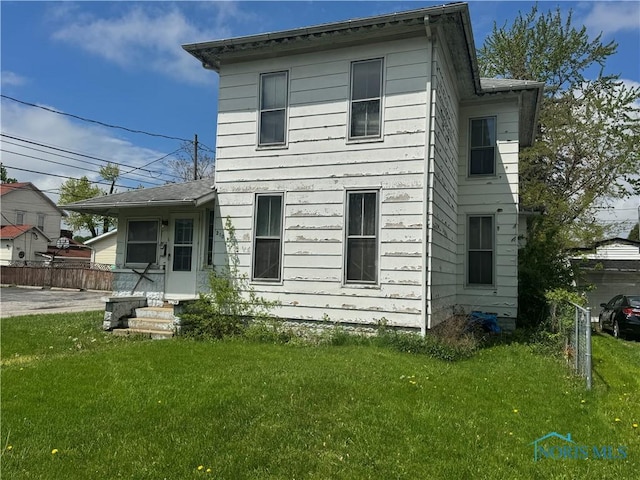 back of house featuring a yard and fence