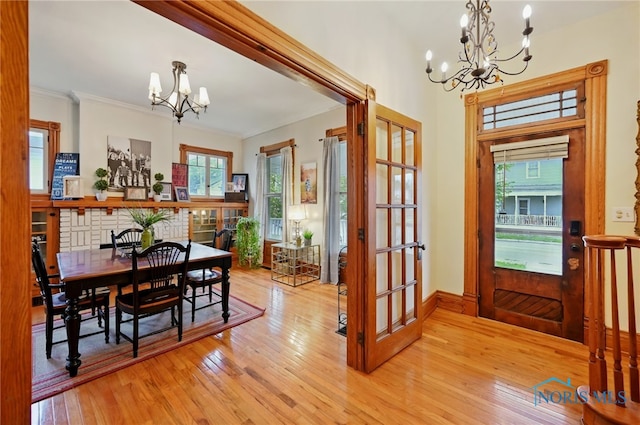 dining space featuring french doors, light wood finished floors, an inviting chandelier, and crown molding