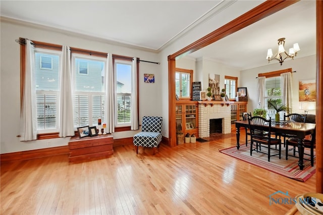 interior space featuring ornamental molding, baseboards, a brick fireplace, wood-type flooring, and a notable chandelier