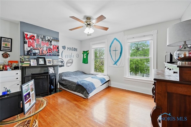 bedroom with ceiling fan, light wood-style flooring, and baseboards