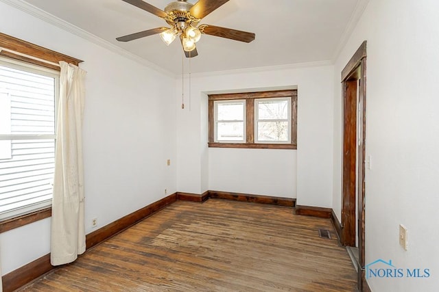 unfurnished room featuring crown molding, baseboards, visible vents, and wood finished floors