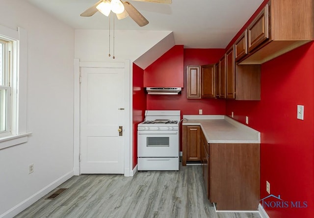 kitchen with under cabinet range hood, ceiling fan, visible vents, gas range gas stove, and light wood-type flooring